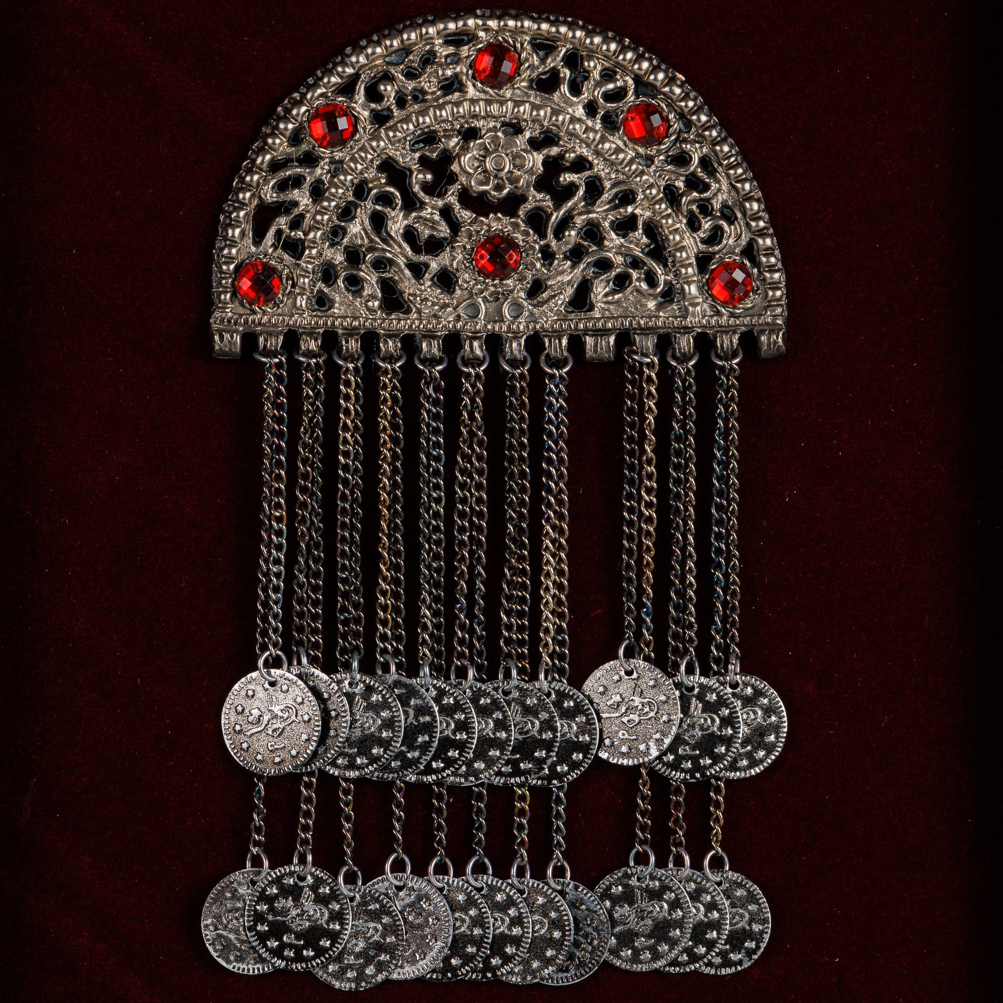 Детален приказ на невестинската пафта од 19-тиот век, истакнувајќи ги црвените камења и висечките синџири со парички кои штитат од уроци.