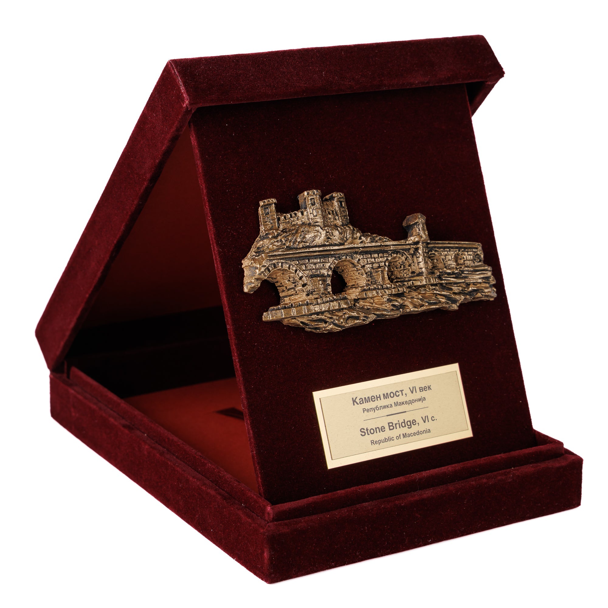 Луксузна бордо кадифена кутија поставена како држач, откривајќи прекрасен метален релјеф на Камениот Мост во Скопје од ВЕКОВИ.