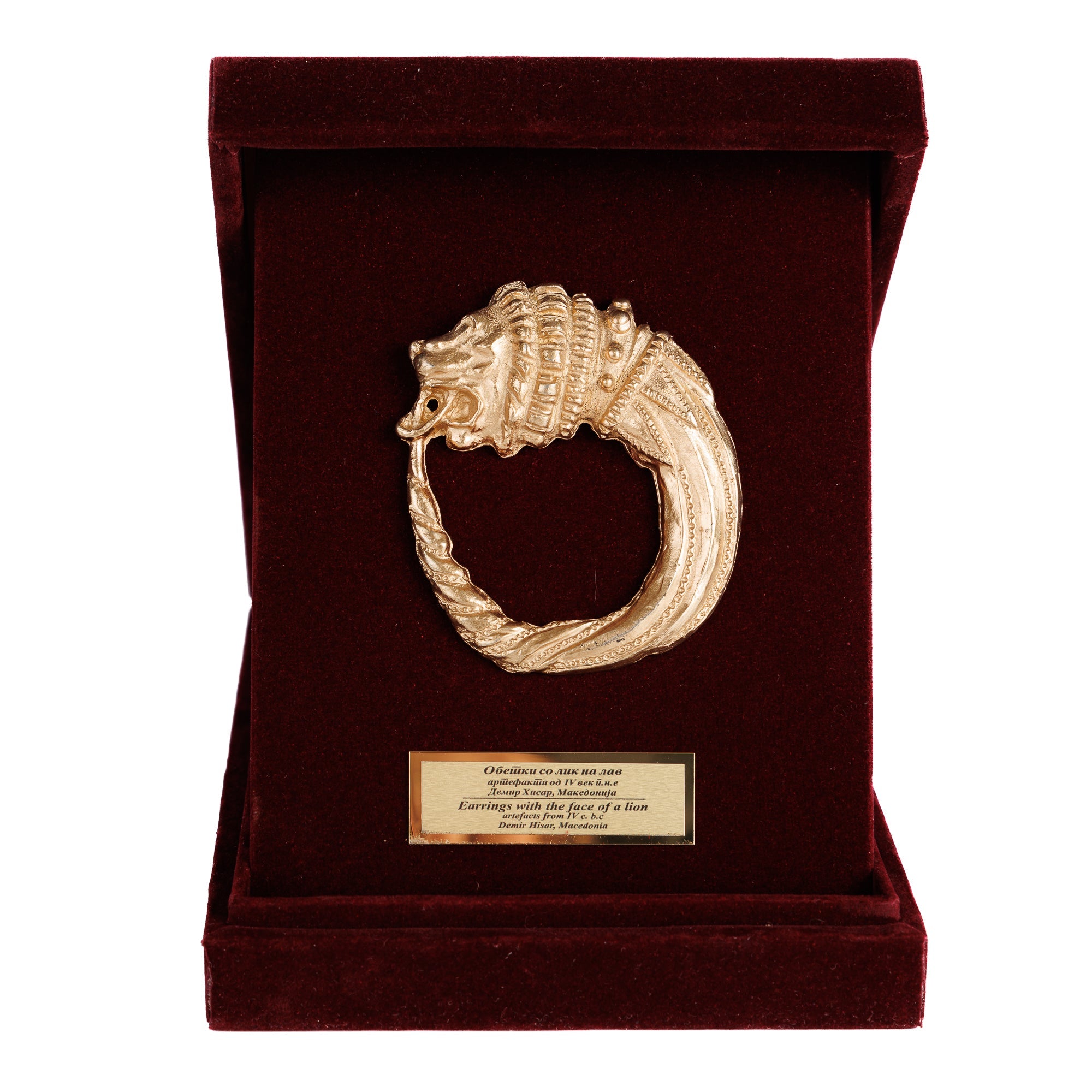 Преден приказ на отворената дипла која ја истакнува репликата на обетката со лавовска глава, симбол на македонската аристократија и моќ.