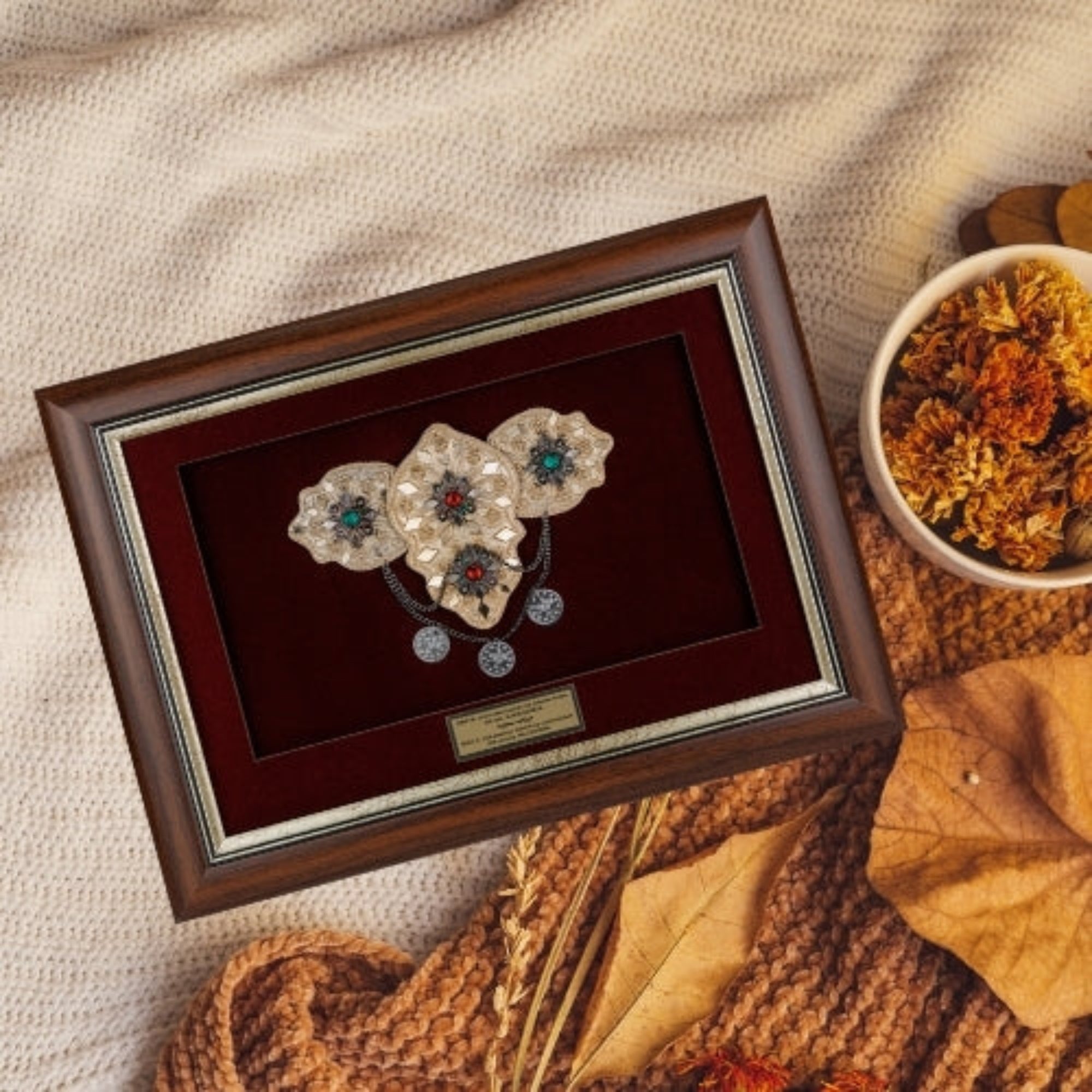 Врамената реплика на македонска невестинска пафта нежно поставена во топол есенски амбиент, идеален сувенир кој симболизира убавина и статус.