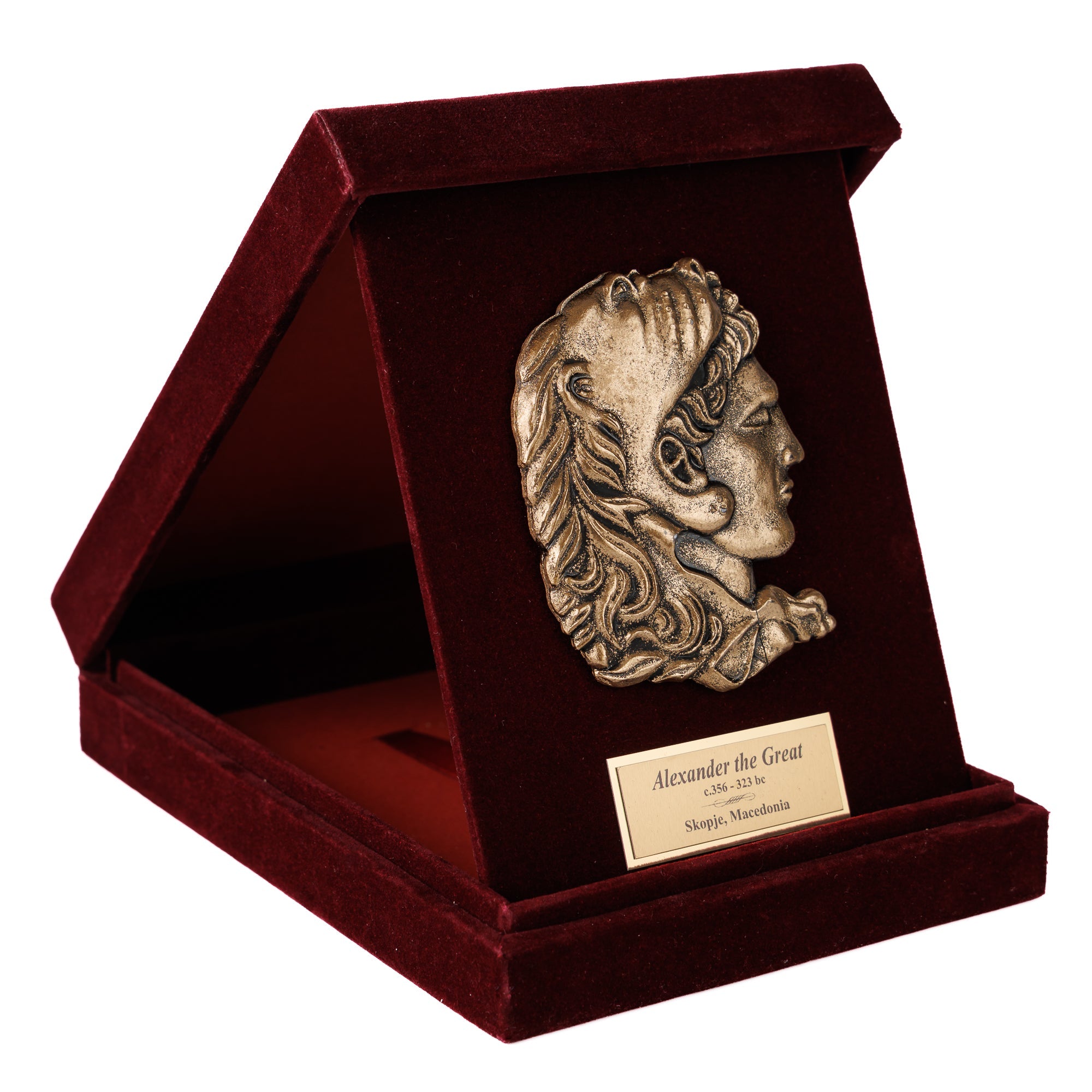 Луксузна бордо кадифена кутија отворена и поставена како држач, откривајќи бронзен релјеф од Александар Велики со лавовска кожа. Престижен подарок од ВЕКОВИ.