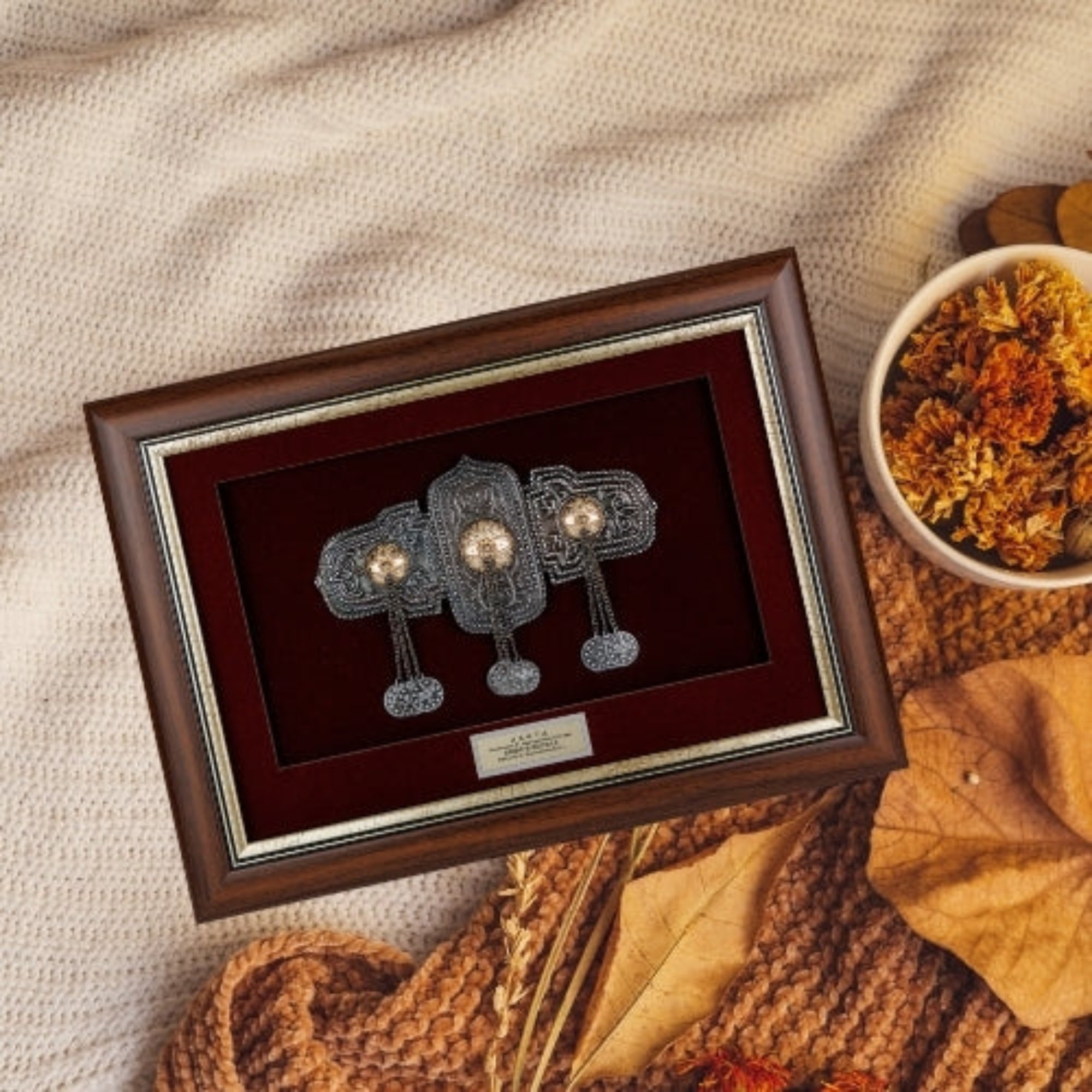 Врамената реплика на невестинска Галичка пафта нежно поставена во топол есенски амбиент, идеален сувенир кој симболизира статус и плодност.